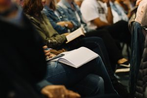 Person in an audience taking notes in a notebook